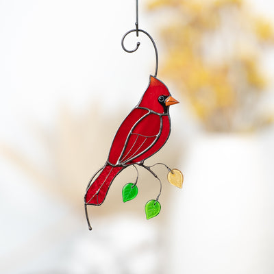 Zoomed red cardinal on the branch with leaves suncatcher