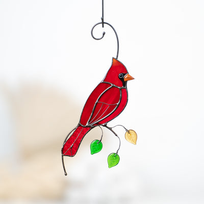 Red winter bird on the branch with leaves suncatcher of stained glass