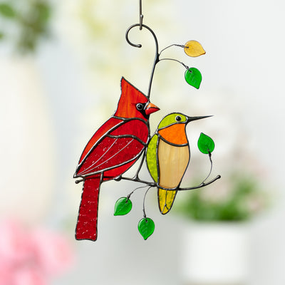 Stained glass window hanging of a red cardinal and green hummingbird sitting on the branch