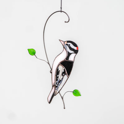Stained glass suncatcher of a downy woodpecker on the branch 