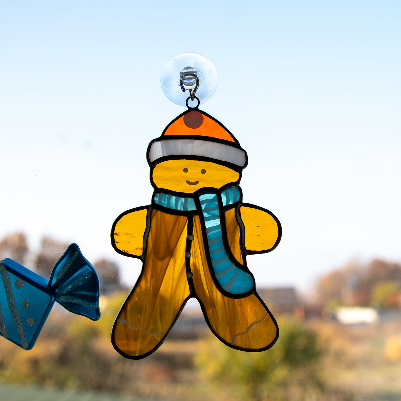 Cute stained glass cookie man wearing a hat and a blue scarf window hanging 