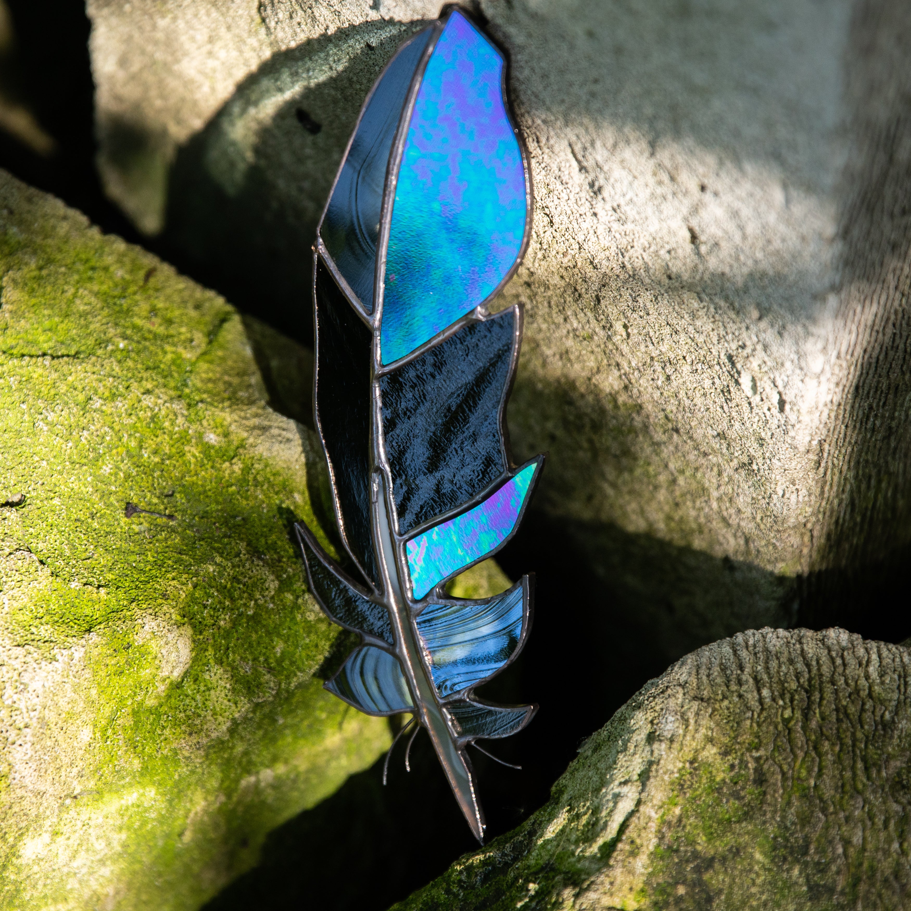 Window hanging of a stained glass raven feather
