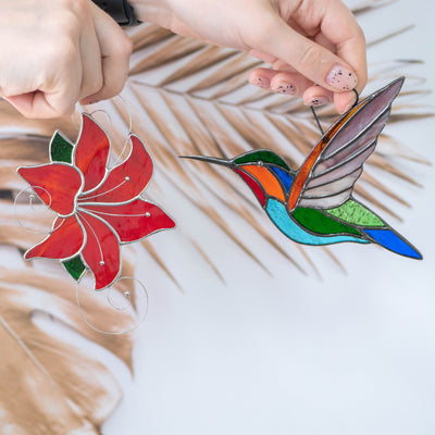 Stained glass hummingbird flying to the red flower window hanging