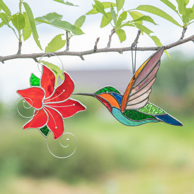 Stained glass colourful hummingbird flying towards the red flower suncatcher