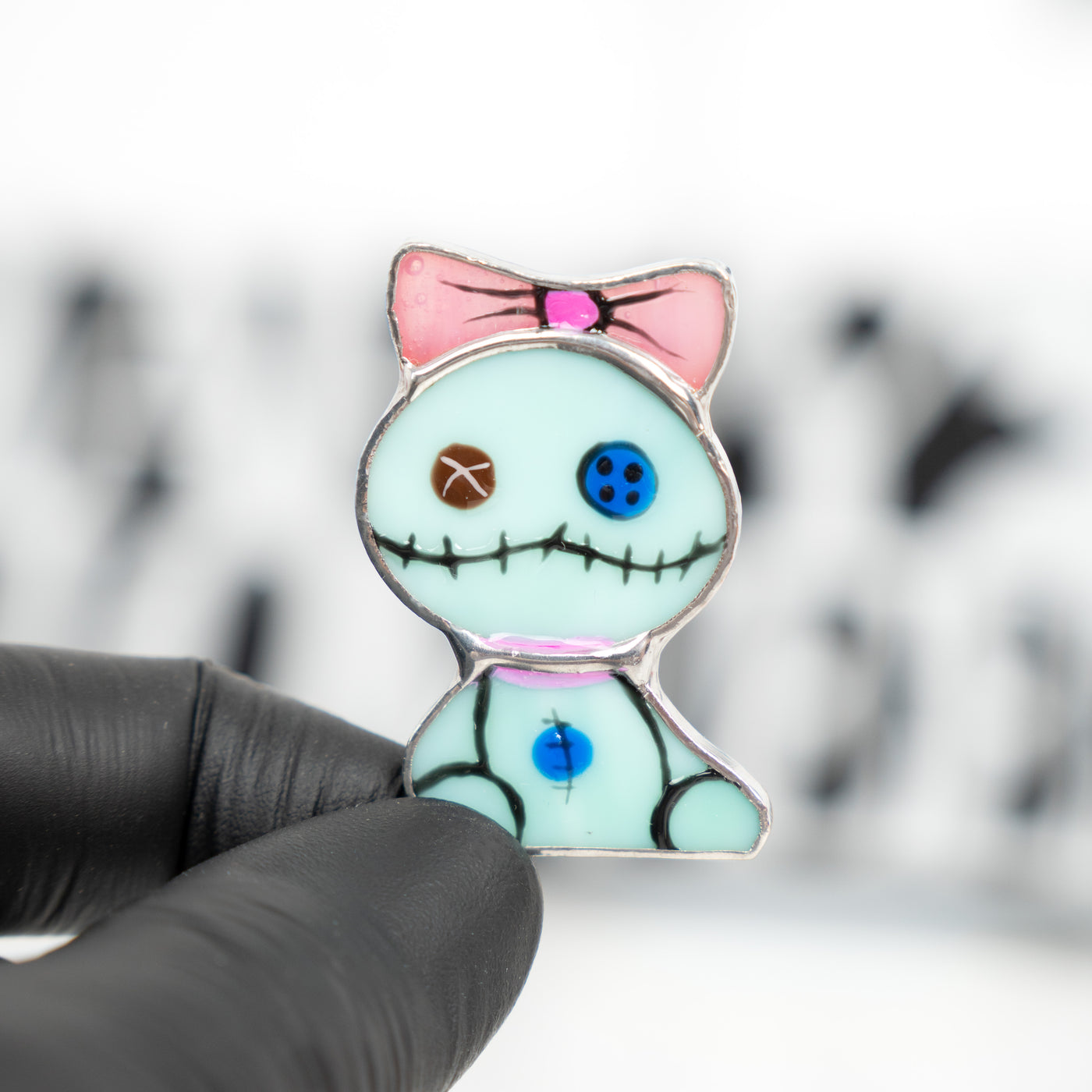 Zoomed stained glass turquoise toy with pink bow pin