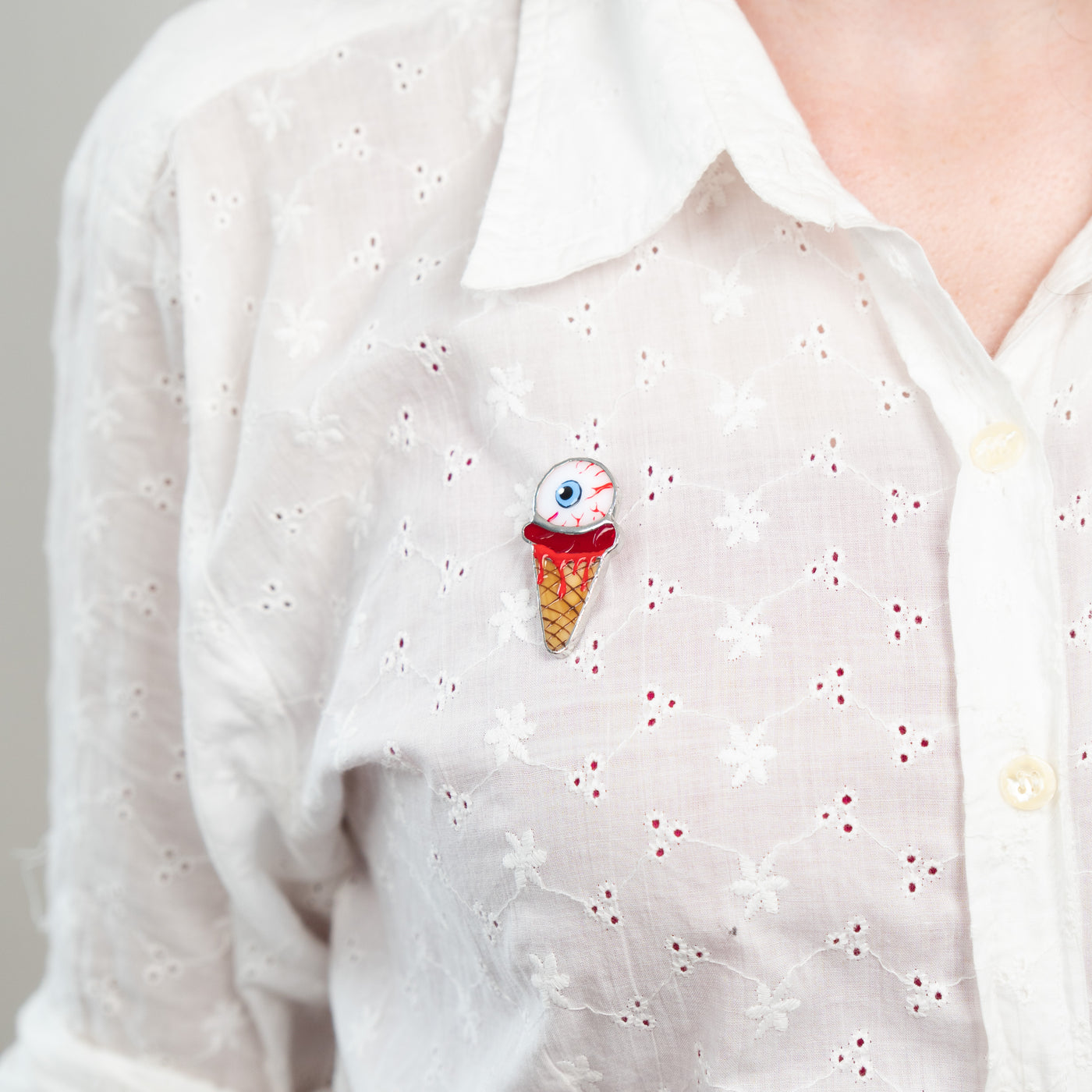Ice-cream with the torn out eye brooch of stained glass on a white shirt