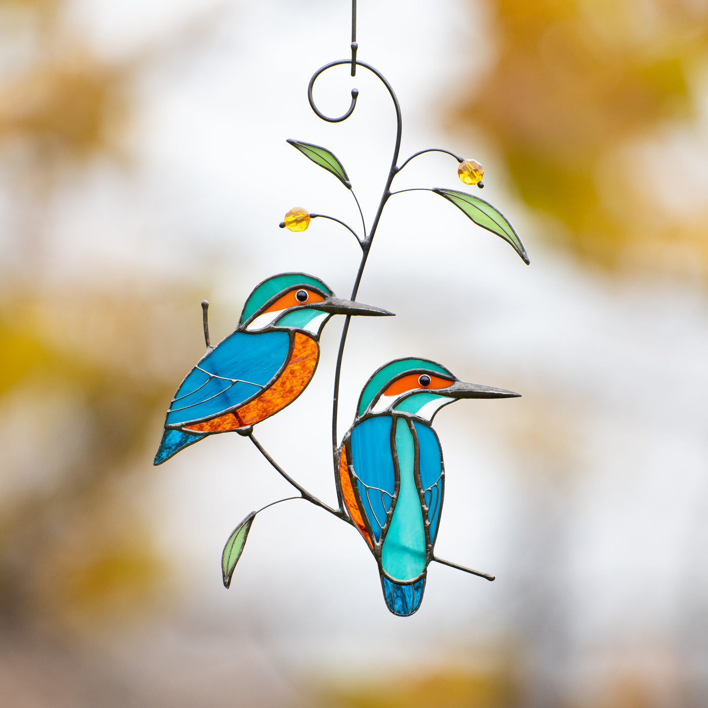 Stained glass window hanging of two kingfishers sitting on the branch