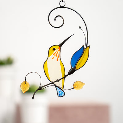 Stained glass yellow hummingbird sitting on the branch with blue and yellow flower window hanging