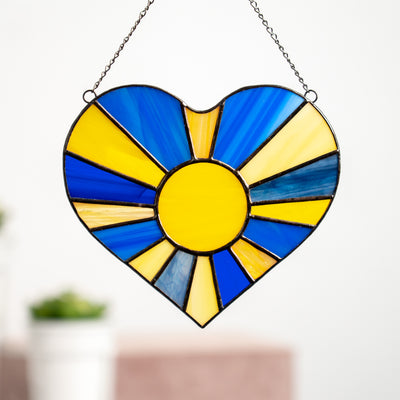 Stained glass blue and yellow heart suncatcher with the sun rays inside of it