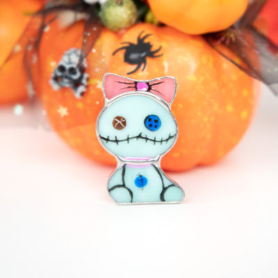Stained glass Halloween brooch of turquoise toy with pink bow 