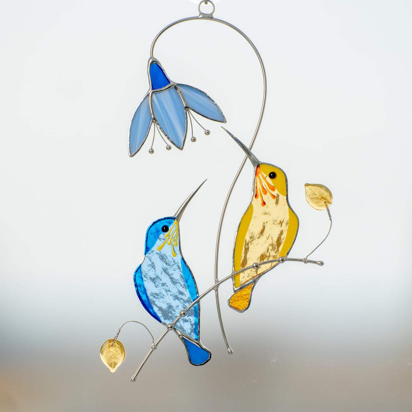 Blue and yellow hummingbirds with the blue flower window hanging of stained glass