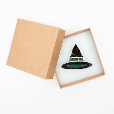 Stained glass pin of a witch hat in a brand box
