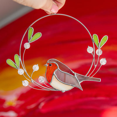 Robin bird of stained glass sitting on the wire mistletoe with leaves and berries