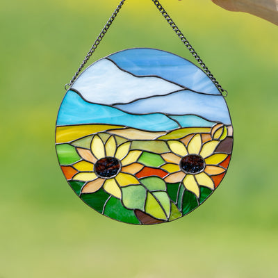 Stained glass round window panel depicting sunflowers and blue skies