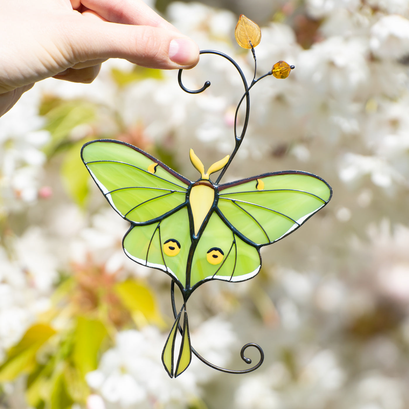 Stained glass green luna moth butterfly on the branch with yellow leaves suncatcher 