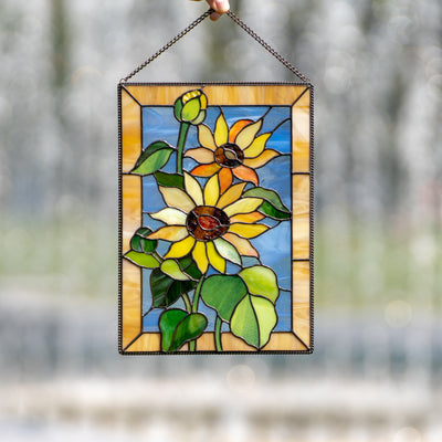 Window hanging with blue and yellow background depicting sunflowers of stained glass