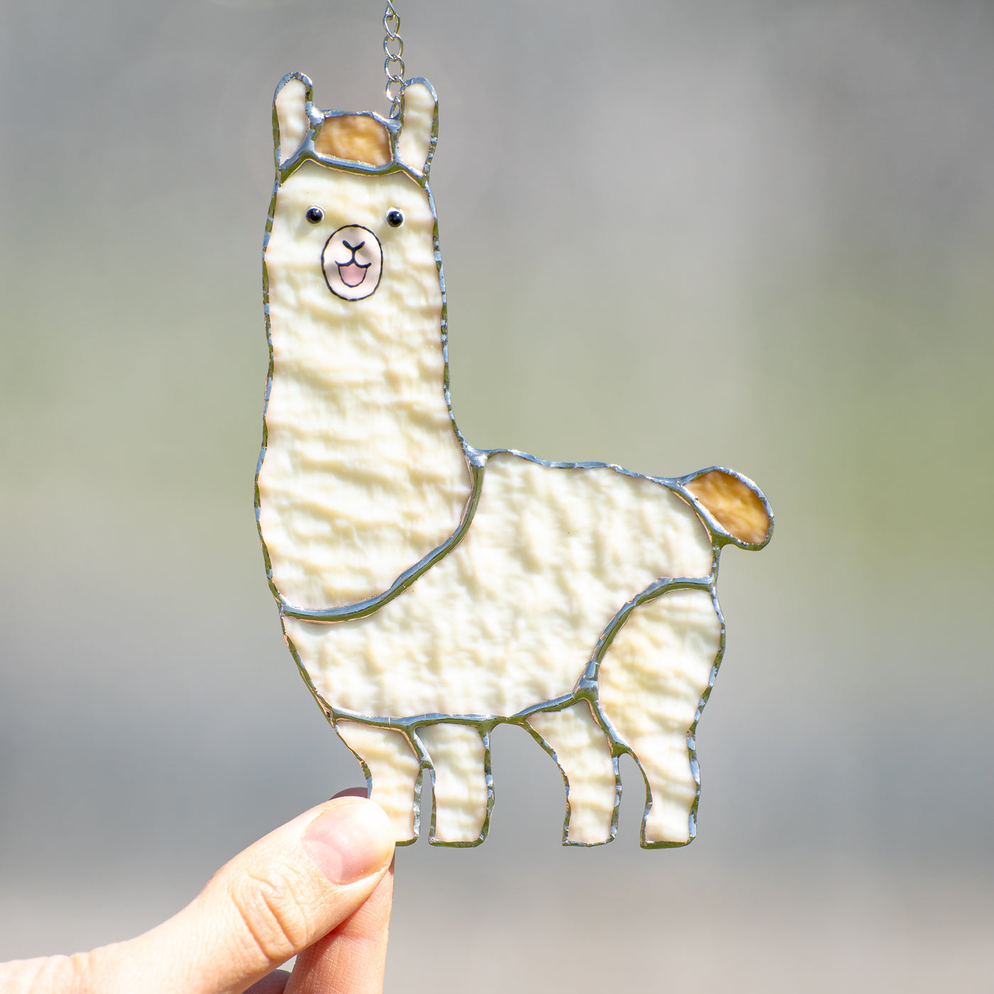 White smiling llama window hanging of stained glass