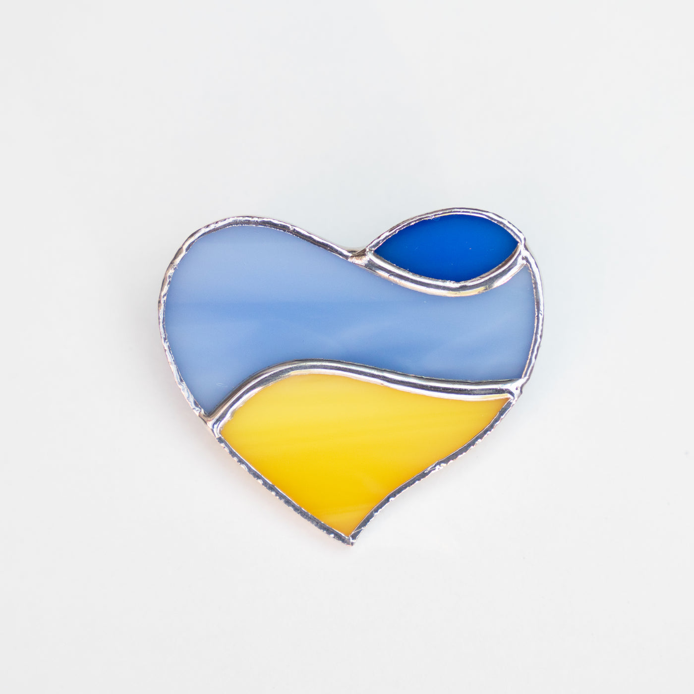 Stained glass heart brooch coloured like Ukrainian flag with light blue in the middle and royal blue above