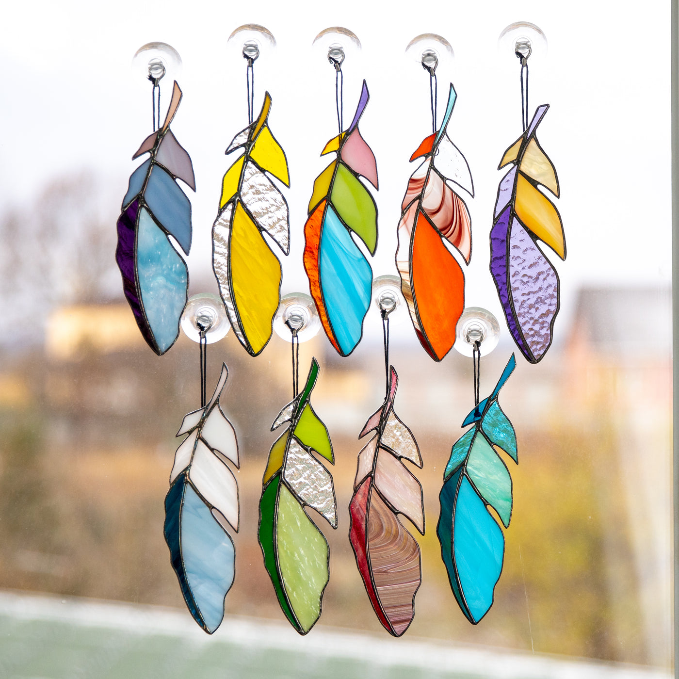 Different variants of colourful stained glass feathers suncatchers