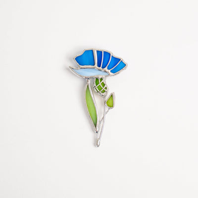 Stained glass brooch of a light-blue and blue cornflower