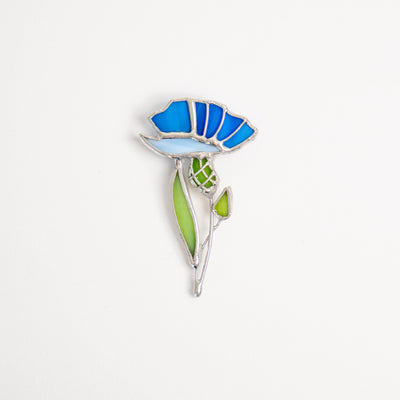 Stained glass brooch of a light-blue and blue cornflower