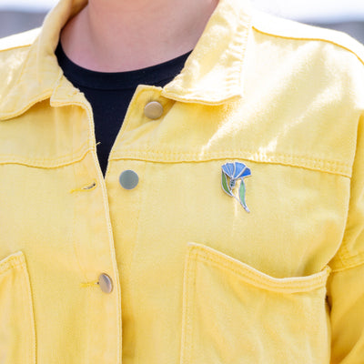 Stained glass blue and navy cornflower brooch on a yellow jacket