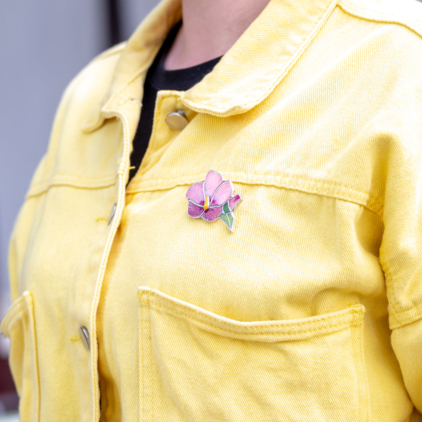 Stained glass pink mallow brooch on a yellow jacket 