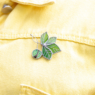 Stained glass brooch of a chestnut on a yellow jacket