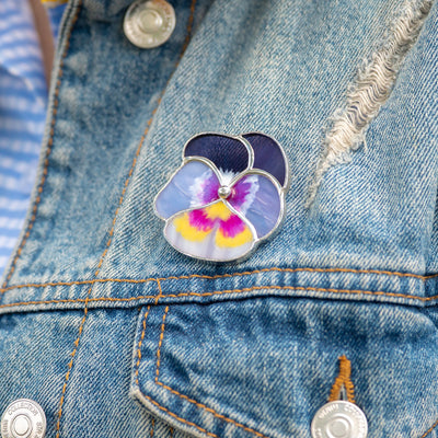 Stained glass purple pansy flower brooch on a jeans jacket