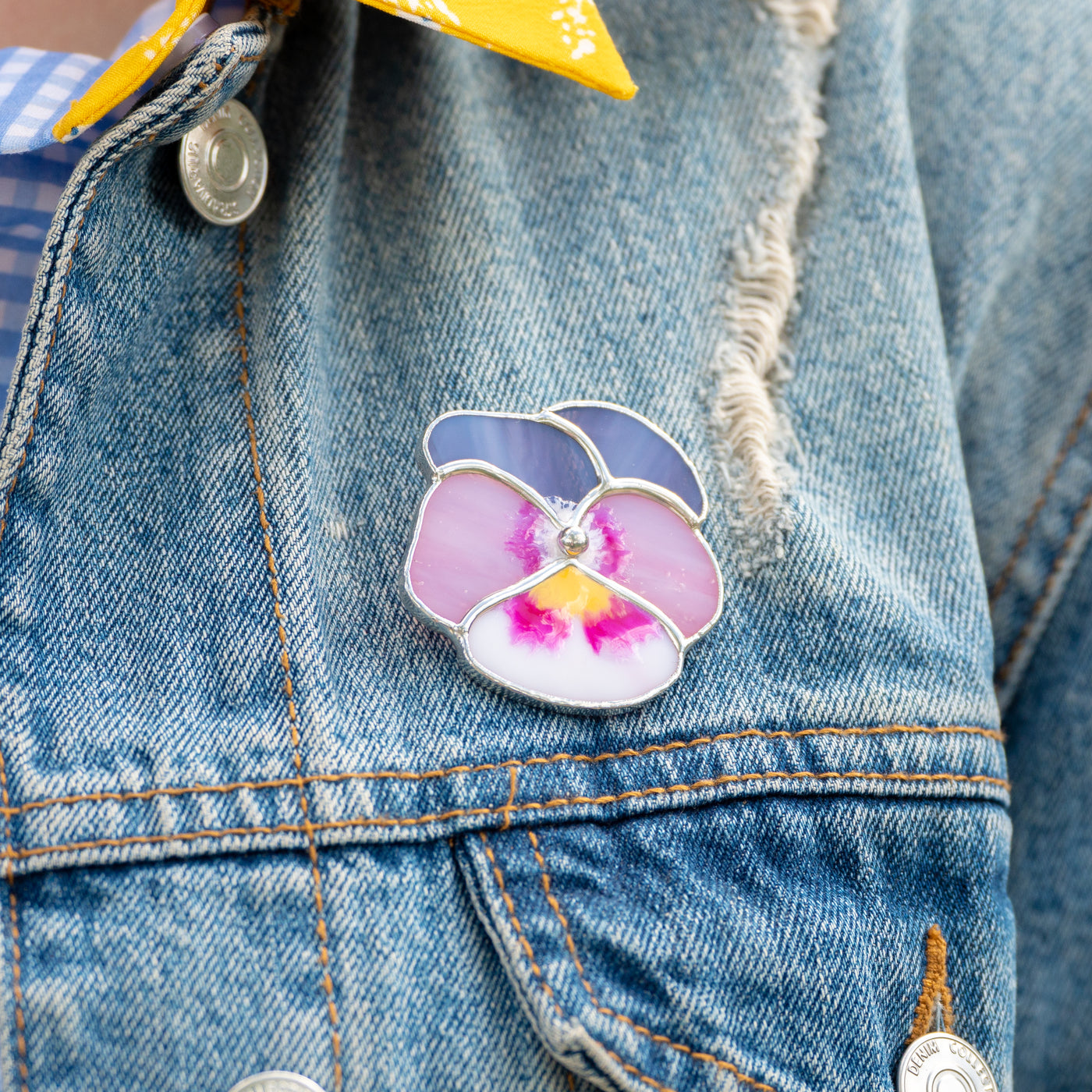 Stained glass pink pansy brooch on a jeans jacket