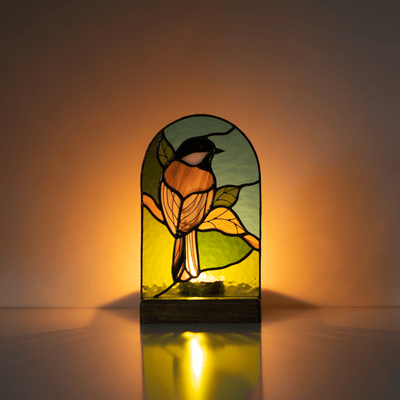 Lit with the candle stained glass panel depicting a chickadee