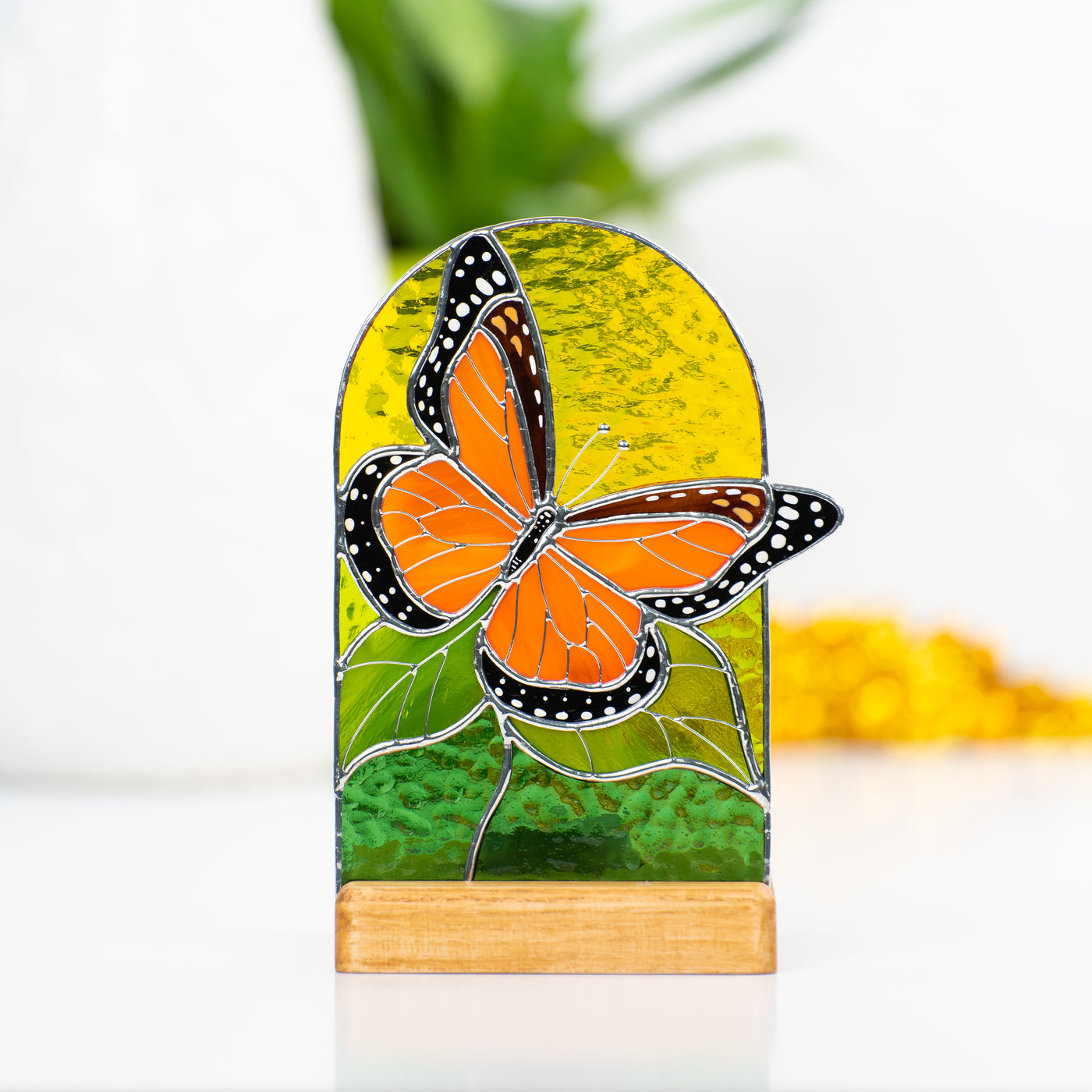 Stained glass panel in a wooden base with the candle behind depicting monarch butterfly