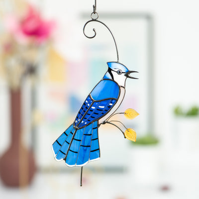 Stained glass blue jay with feathery tail sitting on the branch suncatcher