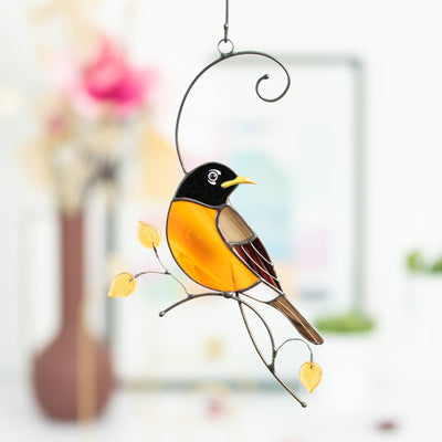Zoomed stained glass Baltimore oriole sitting on the branch with yellow leaves