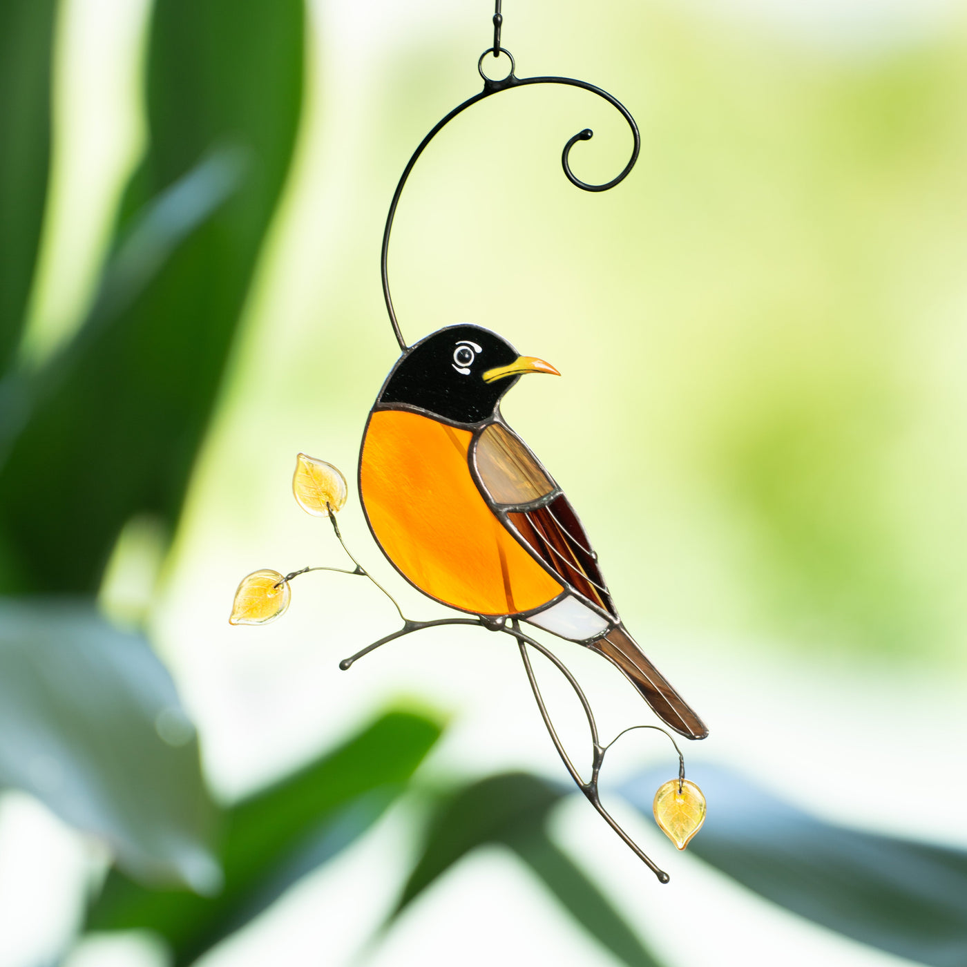 Stained glass suncatcher of a looking right Baltimore oriole sitting on the branch with yellow leaves