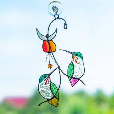Stained glass hummingbirds on the branches with flower above suncatcher