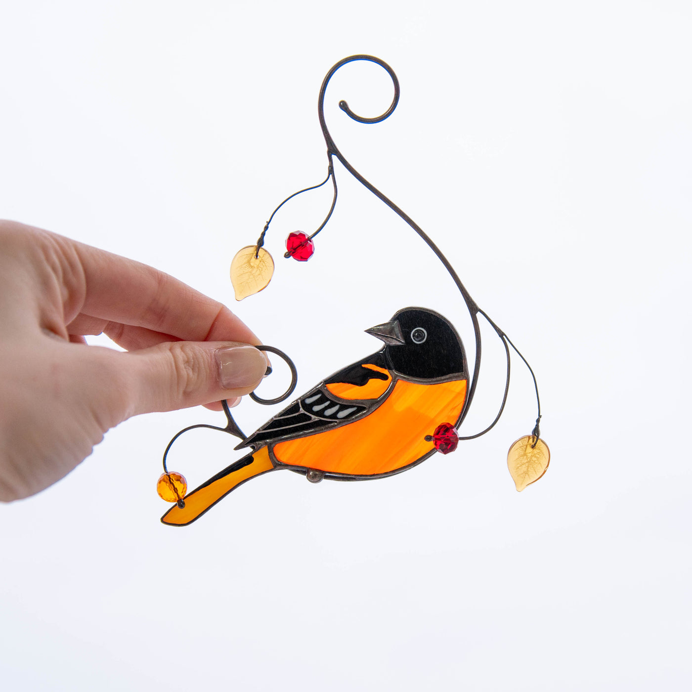 Stained glass Baltimore oriole bird suncatcher on the branch with leaves and berries