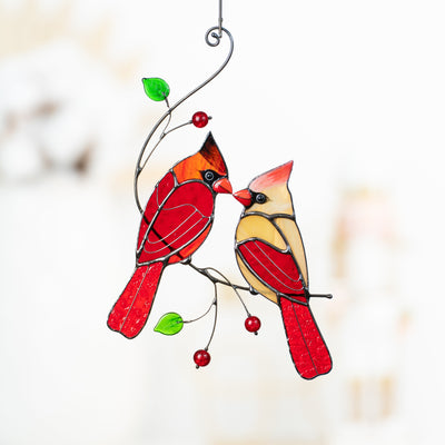 Zoomed stained glass kissing cardinals on the branch with leaves and berries 