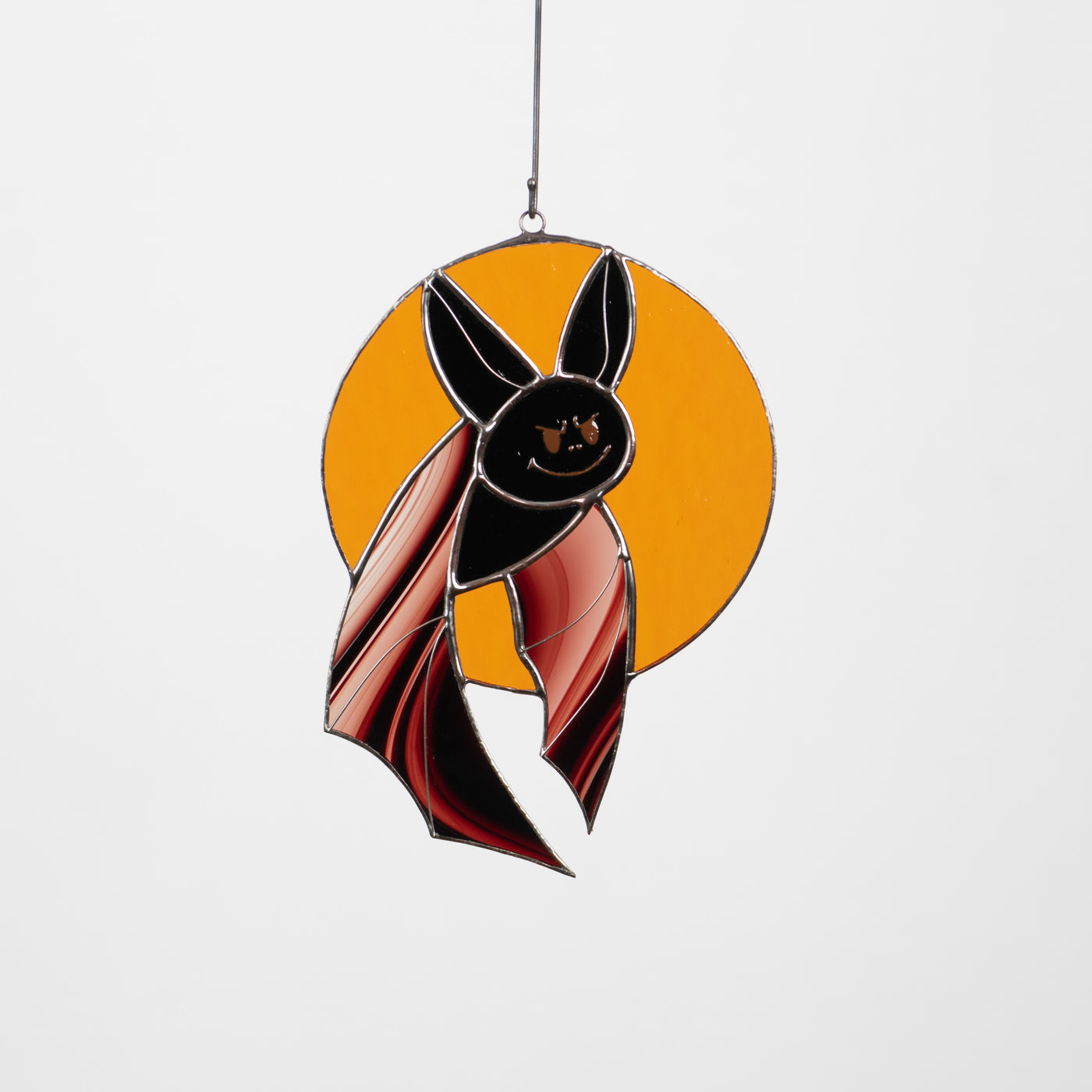 Black bat with brown wings on orange moon suncatcher of stained glass