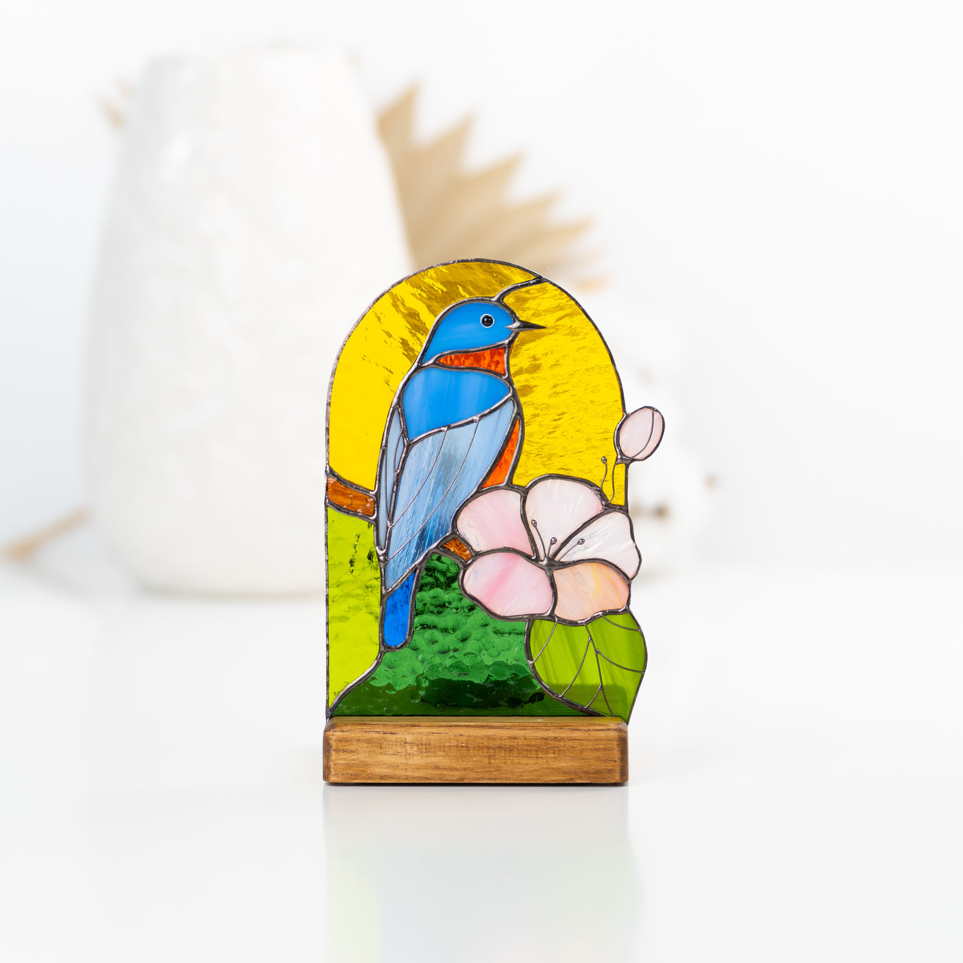 Stained glass panel in a wooden base depicting bluebird and pink flower