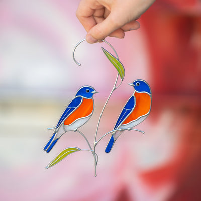 Two stained glass bluebirds on the branch with stained glass leaves