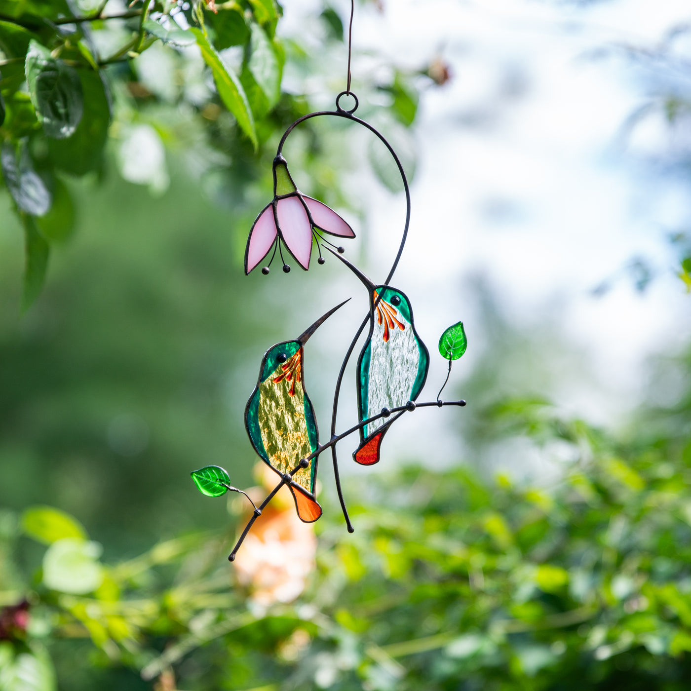 Stained glass suncatcher of a pair of hummingbirds with the pink flower