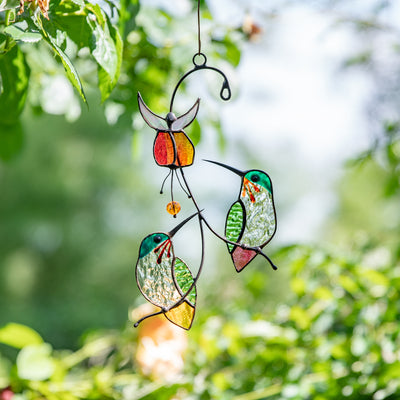 Stained glass hummingbirds sitting on the branch with the red flower above suncatcher