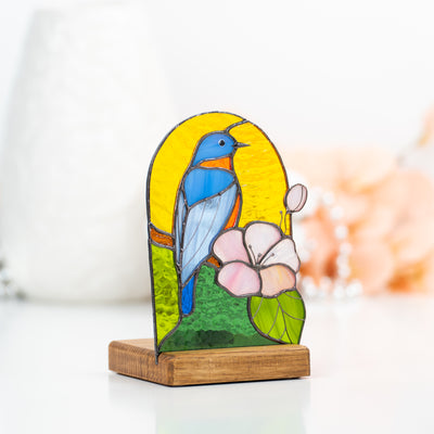 Candle-lit panel in a wooden base depicting bluebird and pink flower of stained glass