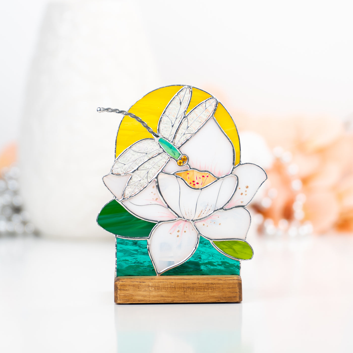 Stained glass panel in a wooden base lit by candle depicting dragonfly with the flower