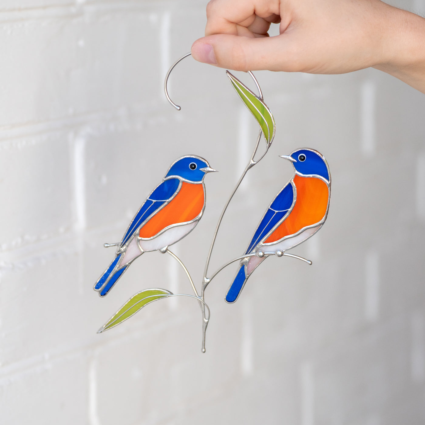 Stained glass suncatcher of two bluebirds sitting on the branch