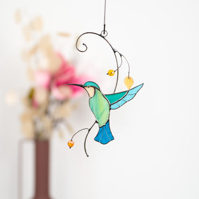 Stained glass colourful hummingbird on the branch suncatcher