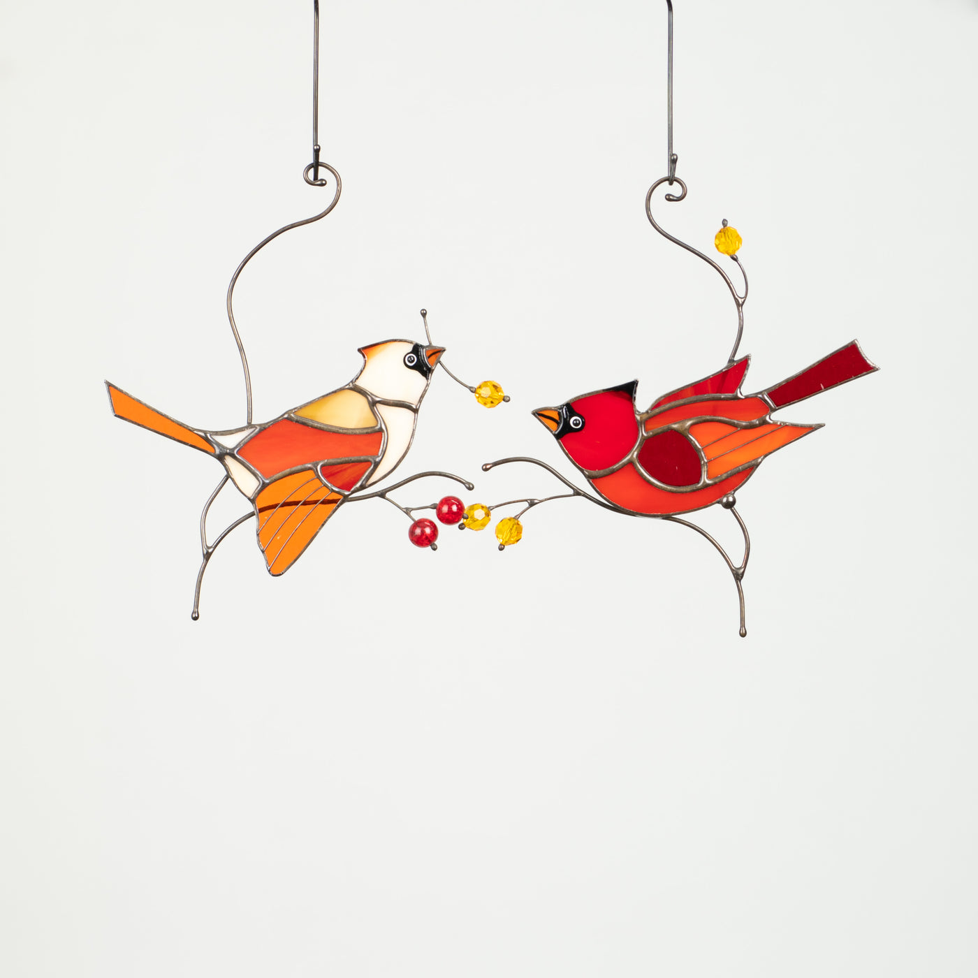 Two stained glass cardinals on branches with leaves and berries sucnatchers