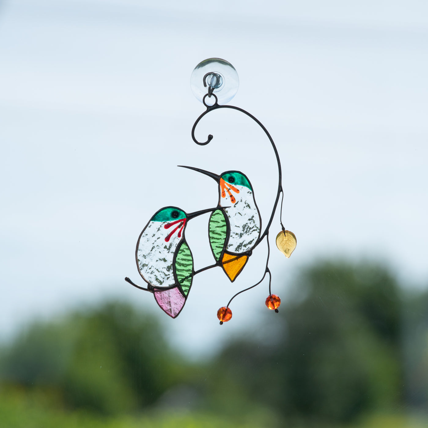 A pair of stained glass hummingbirds on the branch looking in opposite directions suncatcher for window