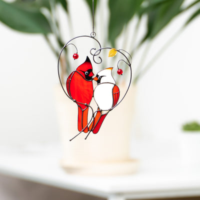 Couple of male and female cardinals sitting on the heart-shaped branch suncatcher